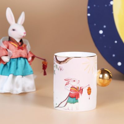 Cốc gốm sứ họa tiết cô thỏ dễ thương, điểm nhấn ở chiếc nút trên thân cốc thay vì tay cầm như bình thường.